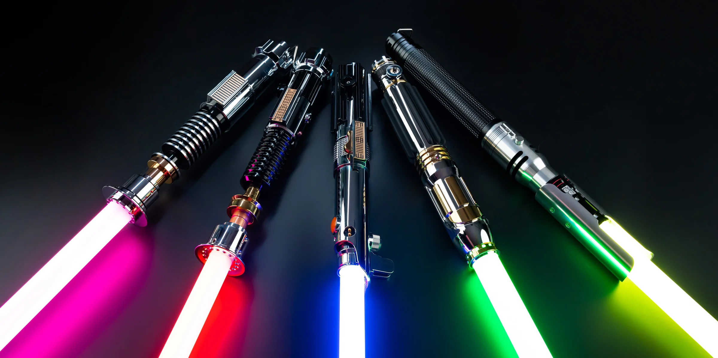 Five lightsabers fanned on a black background: pink